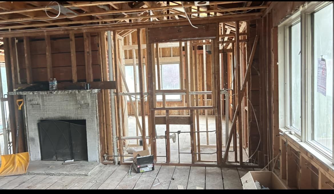 The inside of a house under construction with a fireplace and windows
