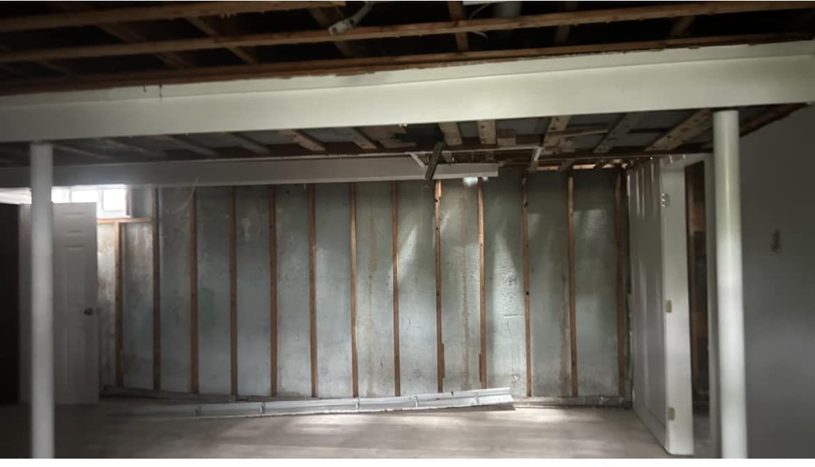 An empty basement with a wooden ceiling and walls.