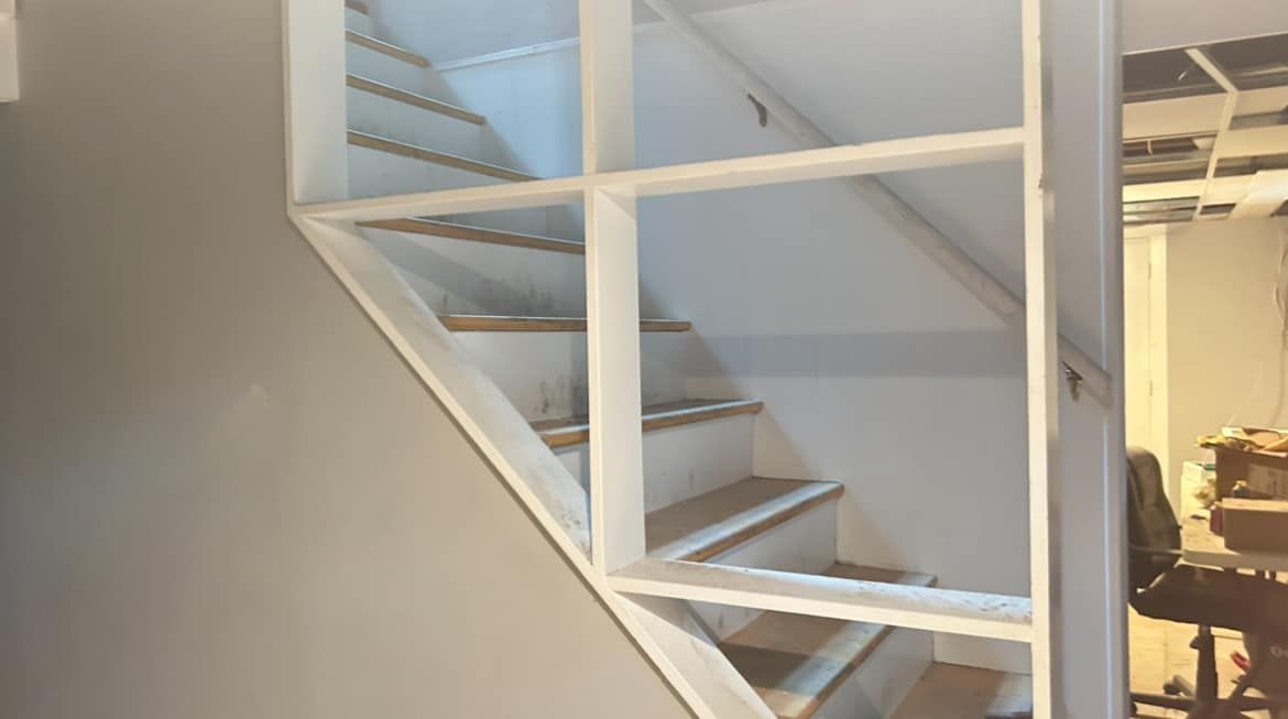A staircase with a shelf between the steps in a room.