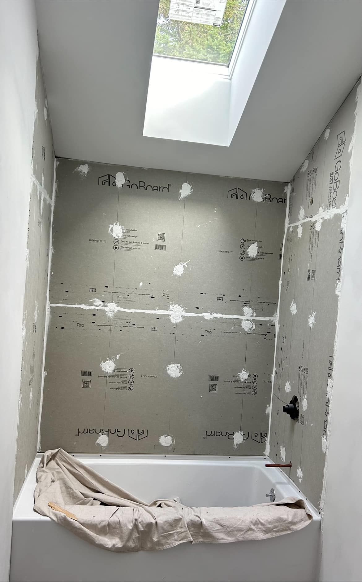 A bathroom under construction with a bathtub and a skylight.