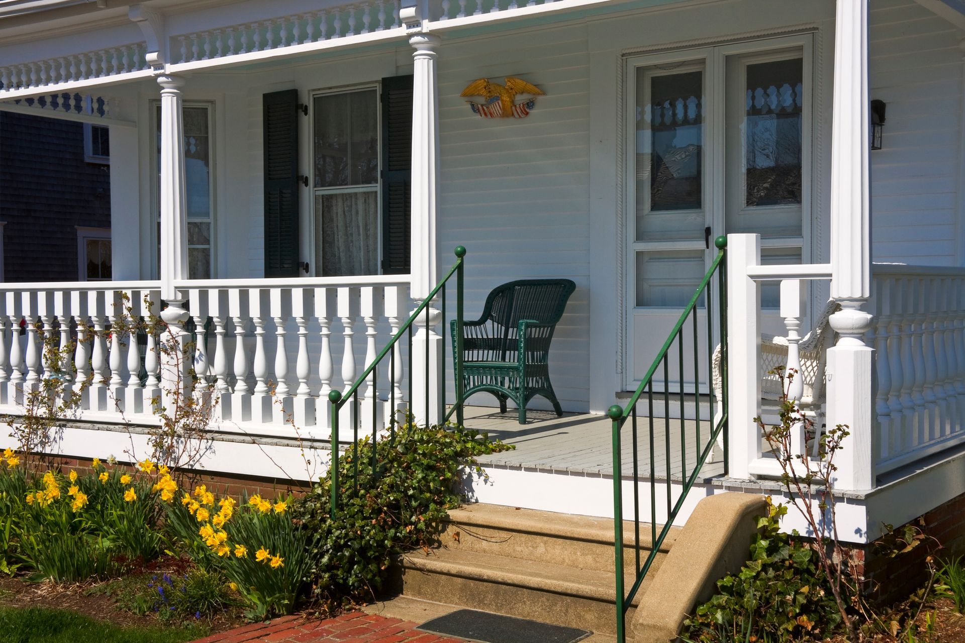 A white deck with a white railing in front of a white house