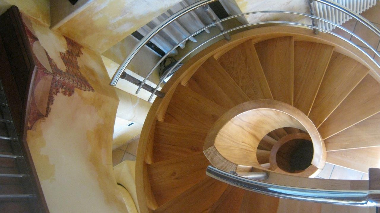 Una scala a chiocciola in legno con ringhiera in metallo
