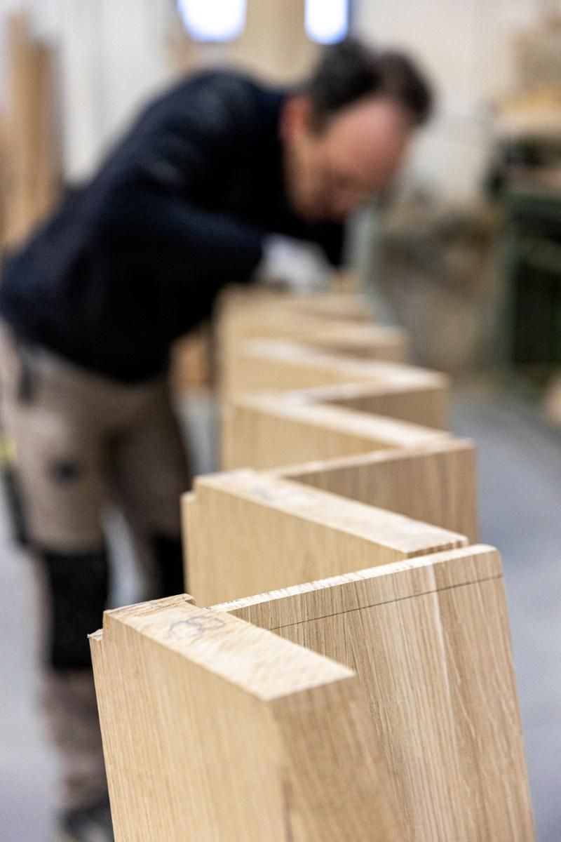 Un uomo sta lavorando su una fila di blocchi di legno in un'officina.
