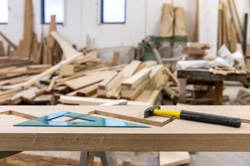Un tavolo di legno con sopra un martello e un righello nella bottega di un falegname.