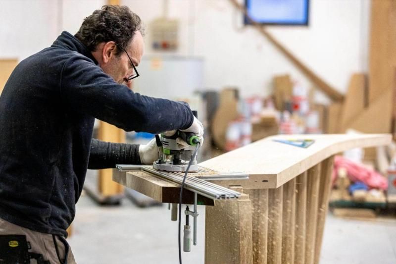 Un uomo sta lavorando su un pezzo di legno in un'officina.