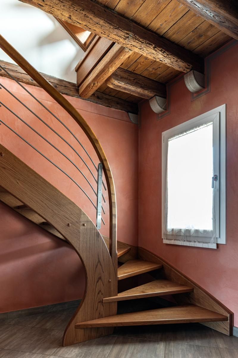 Una scala in legno in una stanza con finestra
