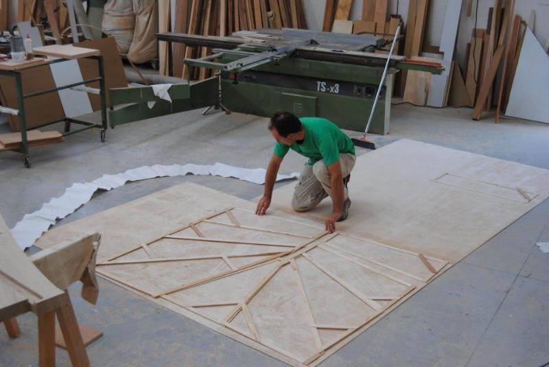 Un uomo con una camicia verde sta misurando un pezzo di legno