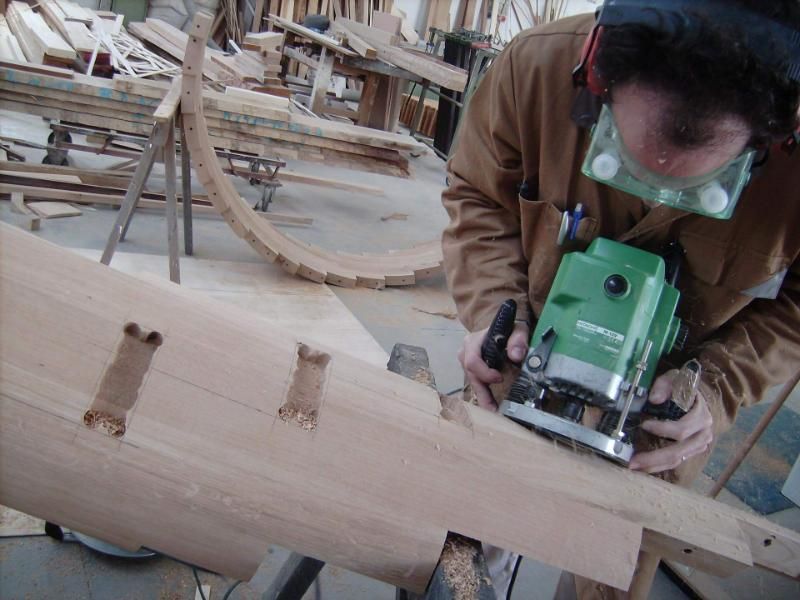 Un uomo usa una fresatrice verde su un pezzo di legno