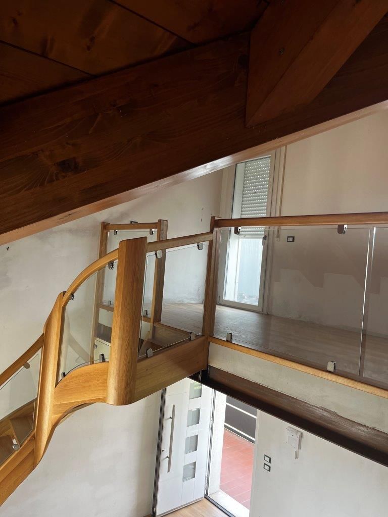 Una scala di legno con ringhiera di vetro