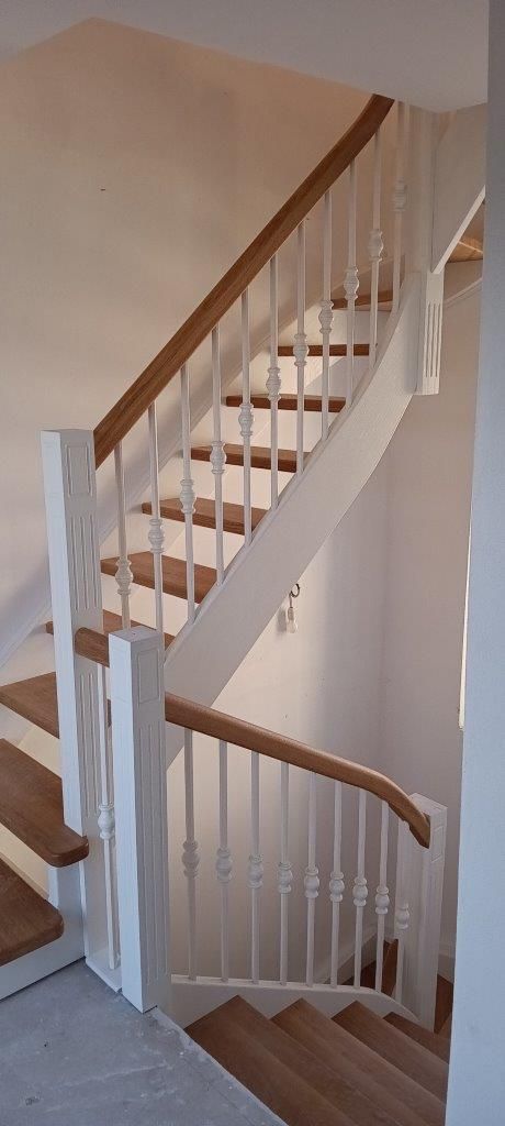 Una scala bianca con gradini e ringhiera in legno.