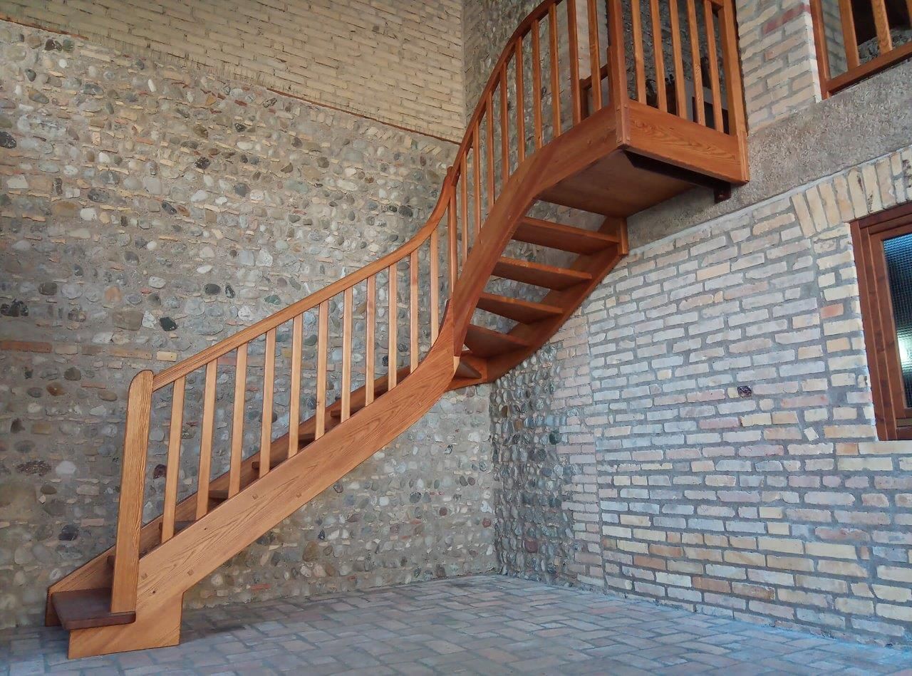 Una scala di legno sale al secondo piano di un edificio in mattoni.