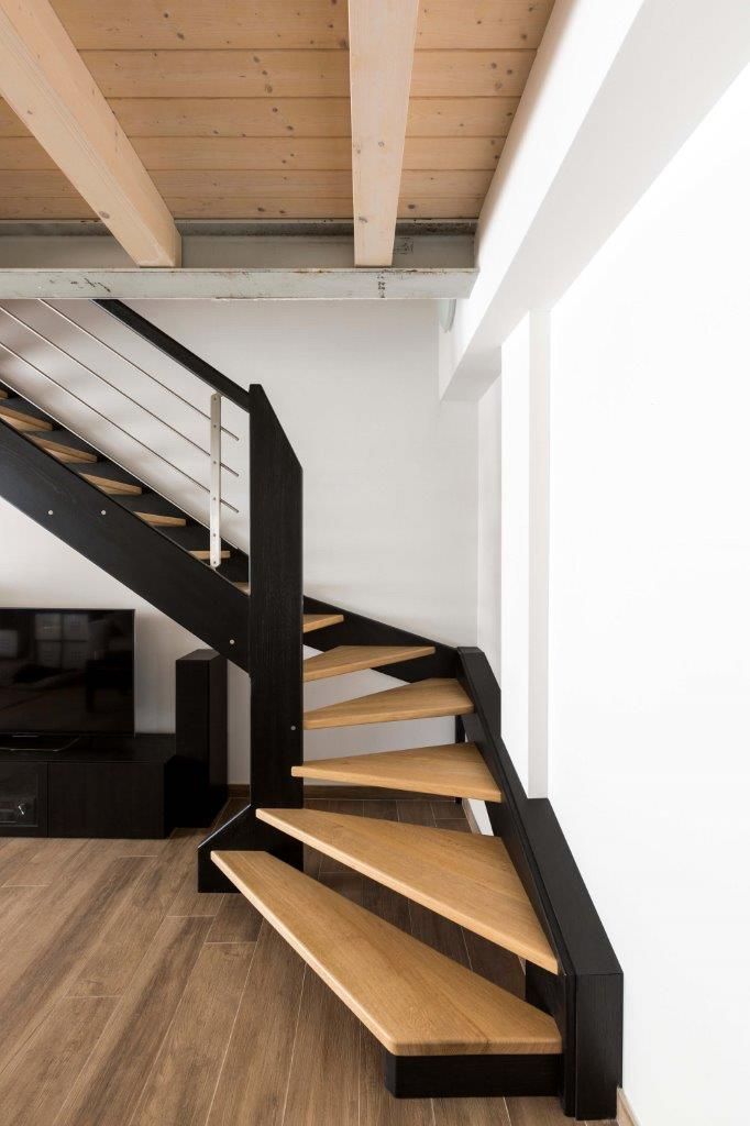 Una scala a chiocciola in legno con ringhiera nera