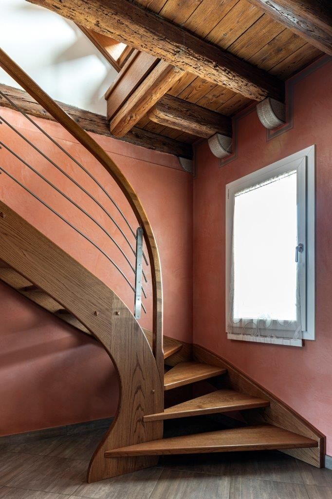 Una scala a chiocciola in legno in una stanza con una finestra.