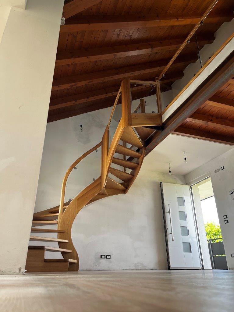 Una scala a chiocciola in legno con ringhiera in vetro
