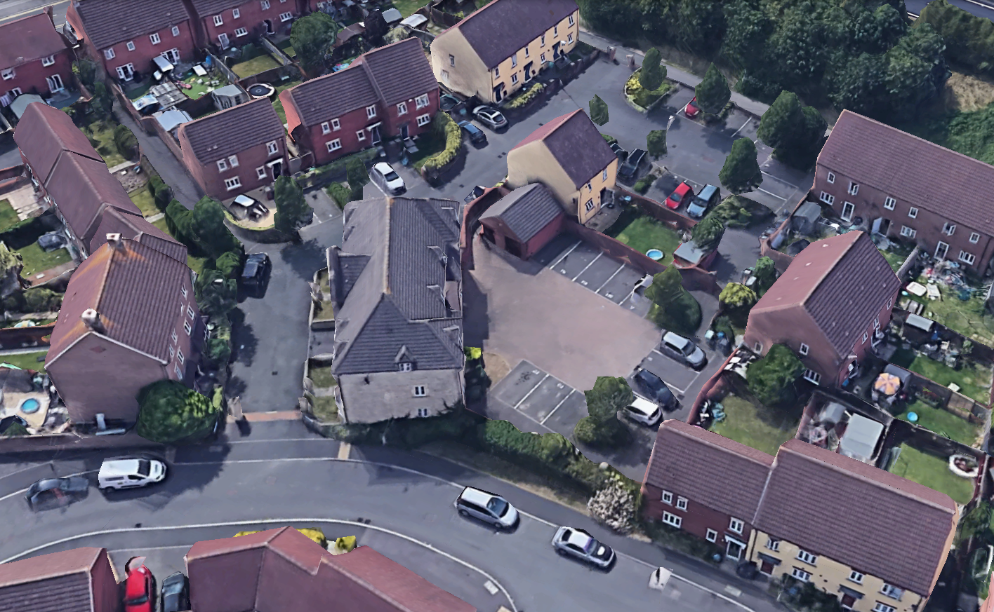 An aerial view of a residential neighborhood with brick houses, a shared parking courtyard, and surrounding paved roads.