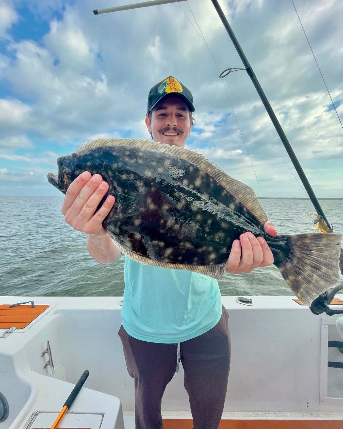 A man is holding a large fish on a boat.