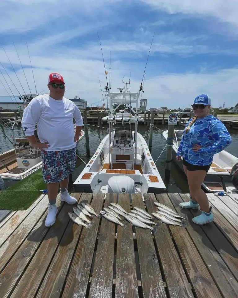 A man and a woman are standing on a dock next to a boat.