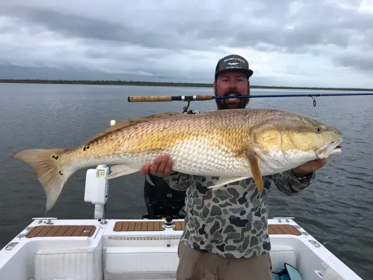 A man is holding a large fish on a boat in the water.