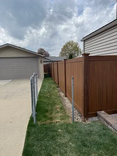 A vinyl fence surrounds a lush green yard in front of a house.