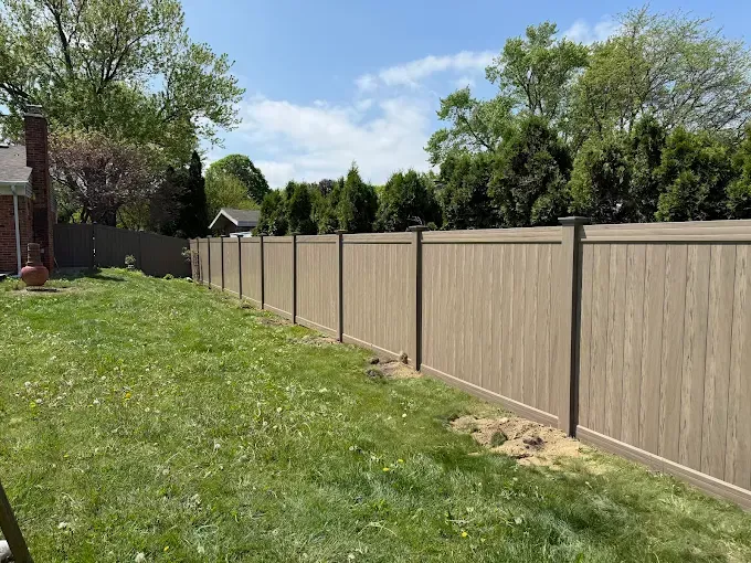 A wooden fence surrounds a lush green lawn in a backyard.
