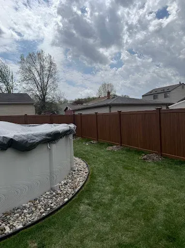 There is a pool in the backyard with a vinyl fence around it.