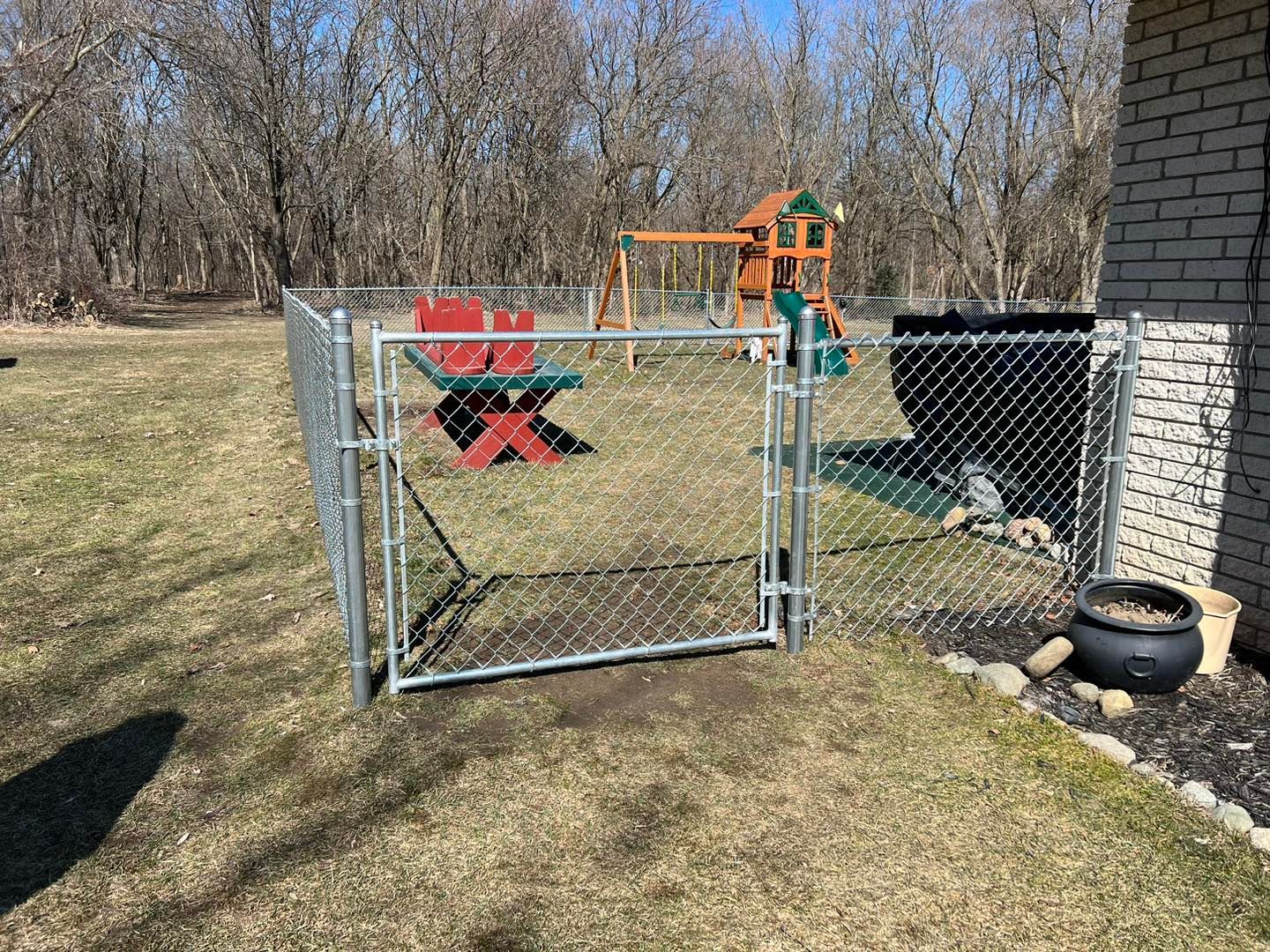 a chain link fence surrounds a backyard with a swing set.