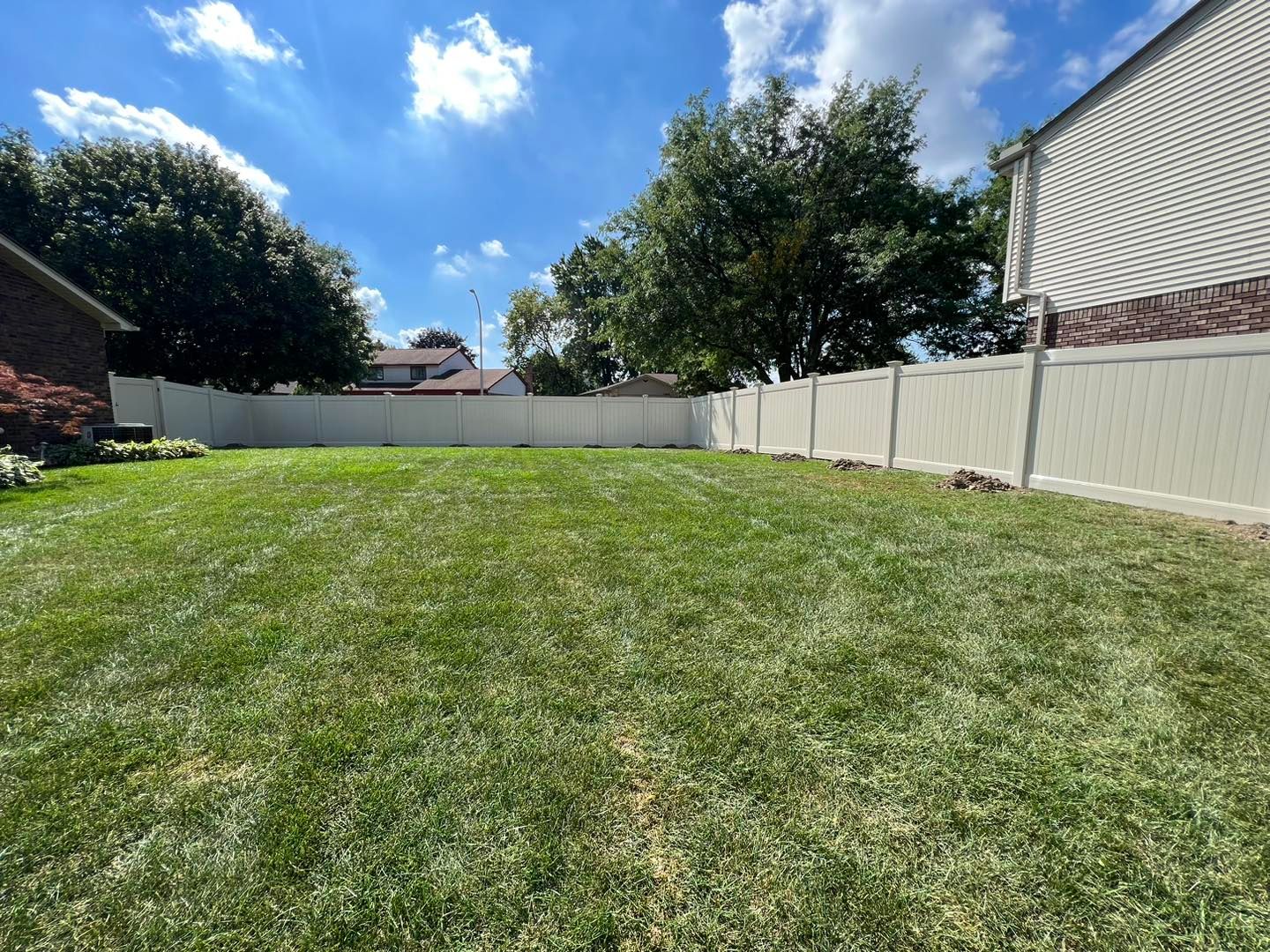 a white fence surrounds a lush green yard.