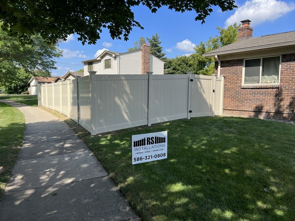 A white fence is in front of a brick house