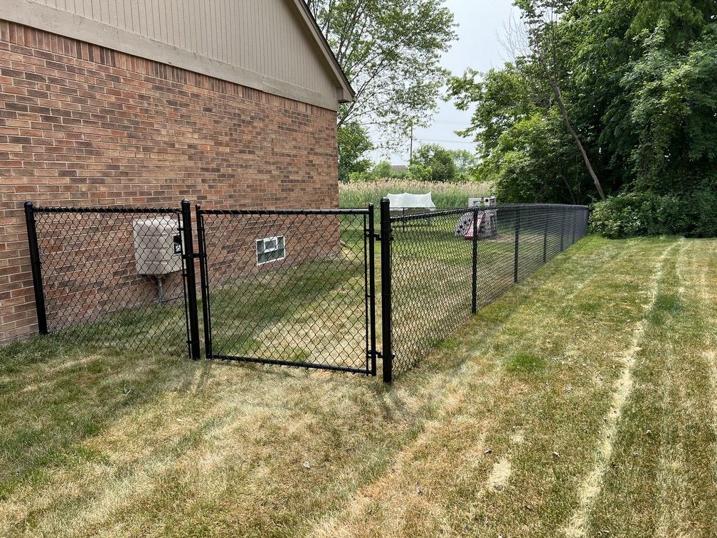 A black chain link fence surrounds a lush green yard.