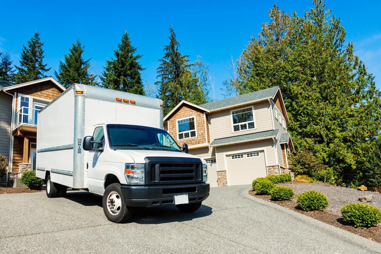 A white moving truck is parked in front of a house.