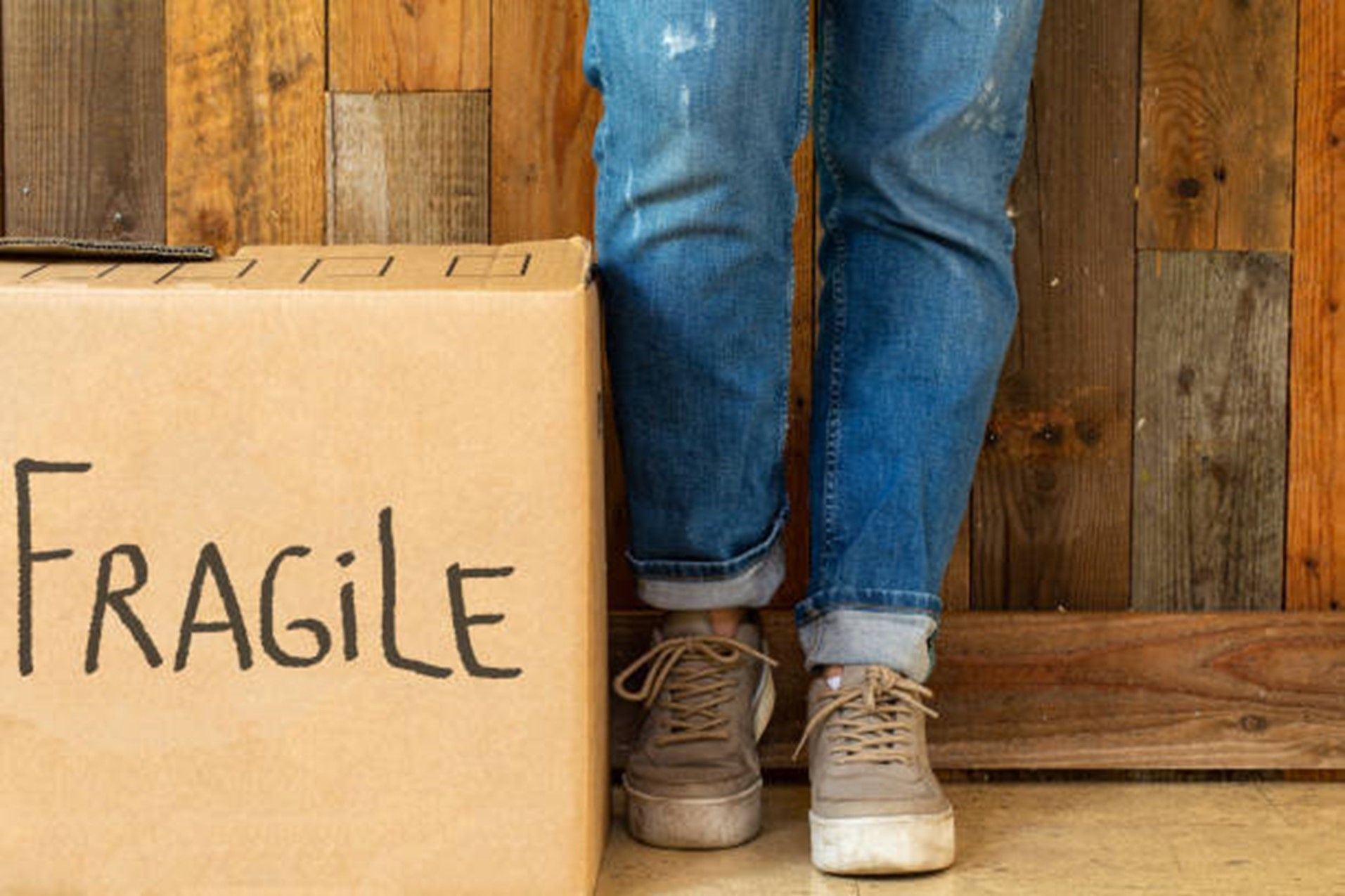 A person is standing next to a cardboard box that says `` fragile ''.