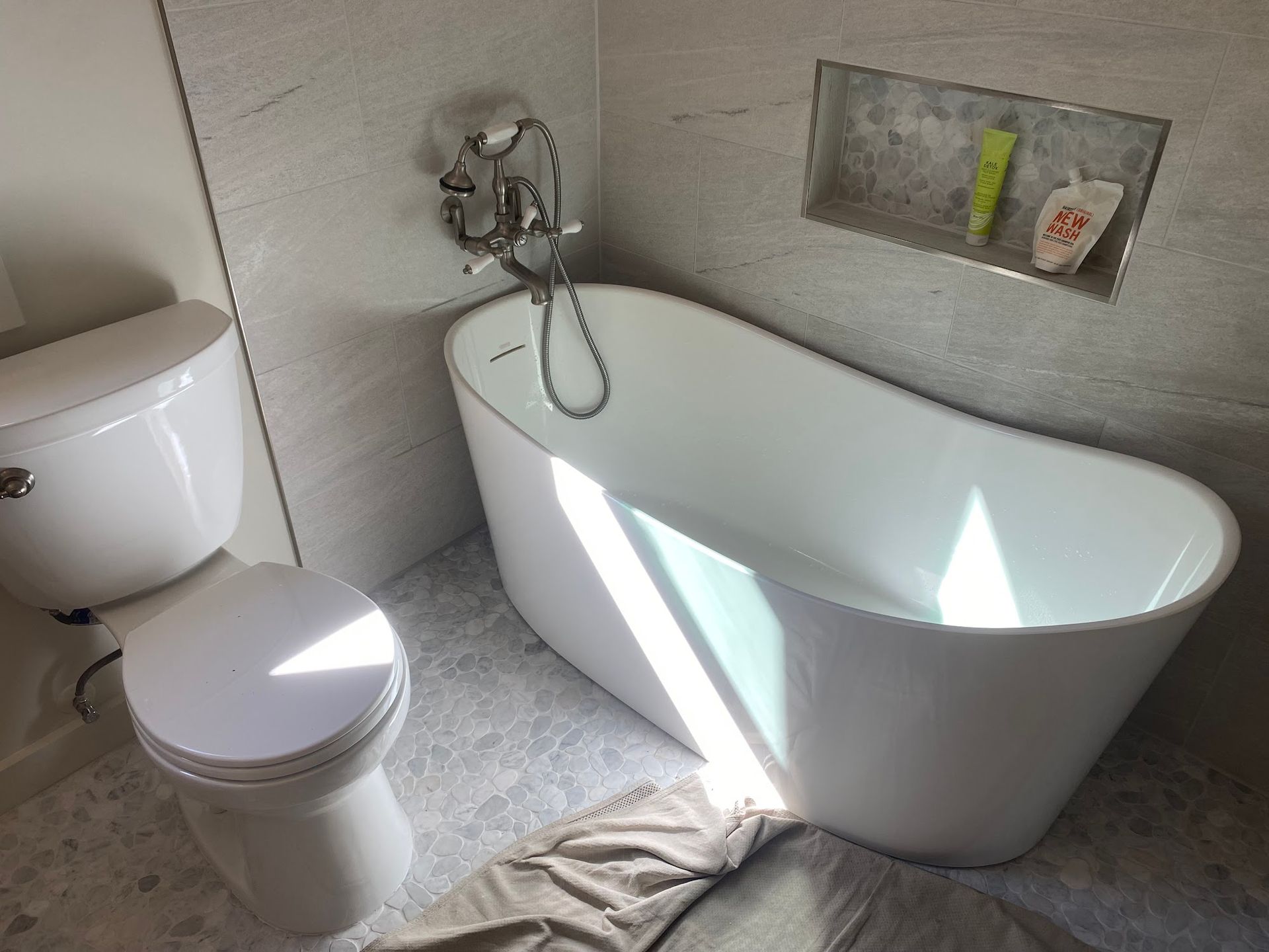 White bathtub and toilet in a modern bathroom with gray tile.
