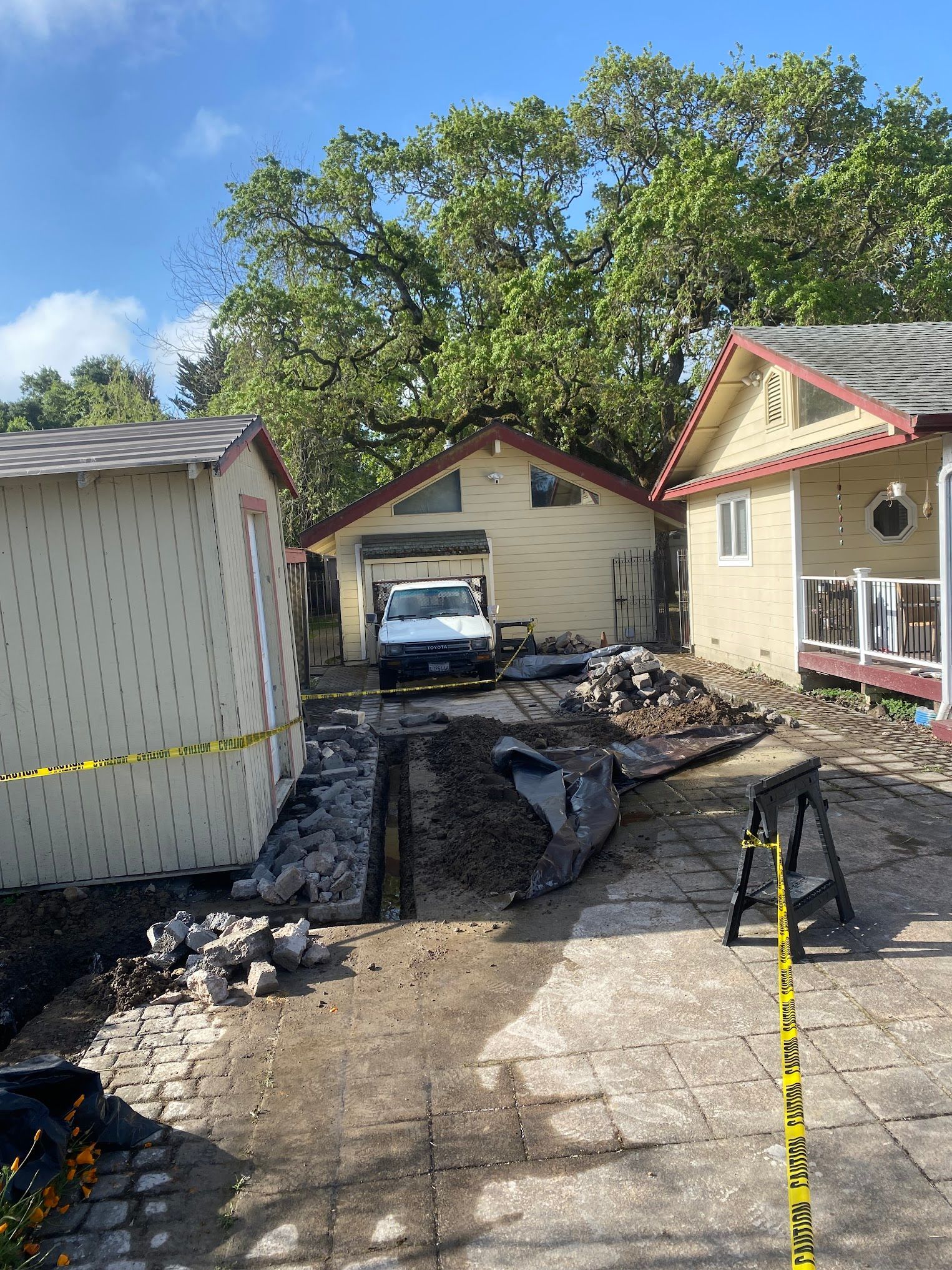 Construction site between three light-colored buildings, with a white van, dirt, and debris; blue sky.