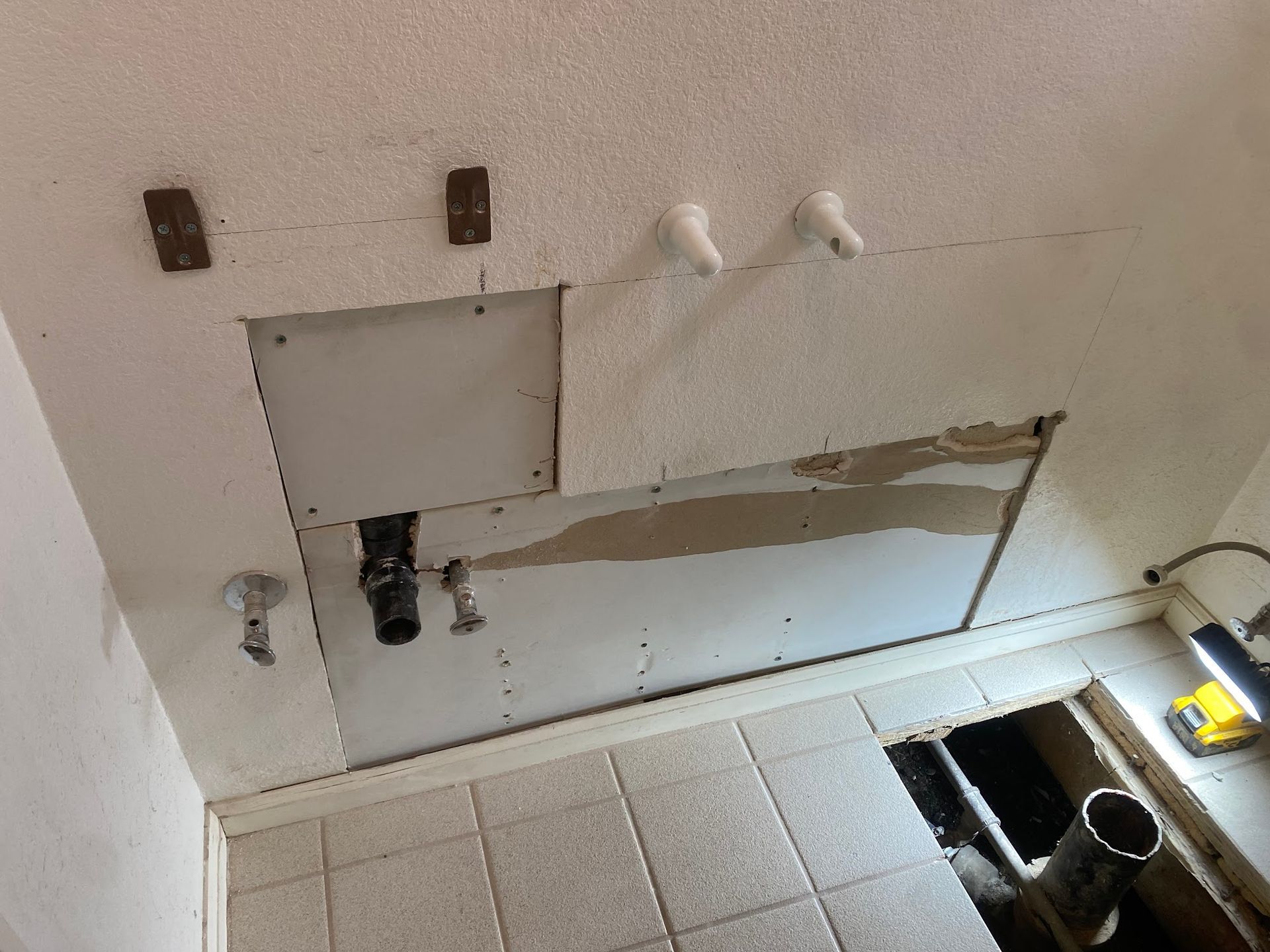 Ceiling with exposed plumbing, missing drywall, and electrical components.