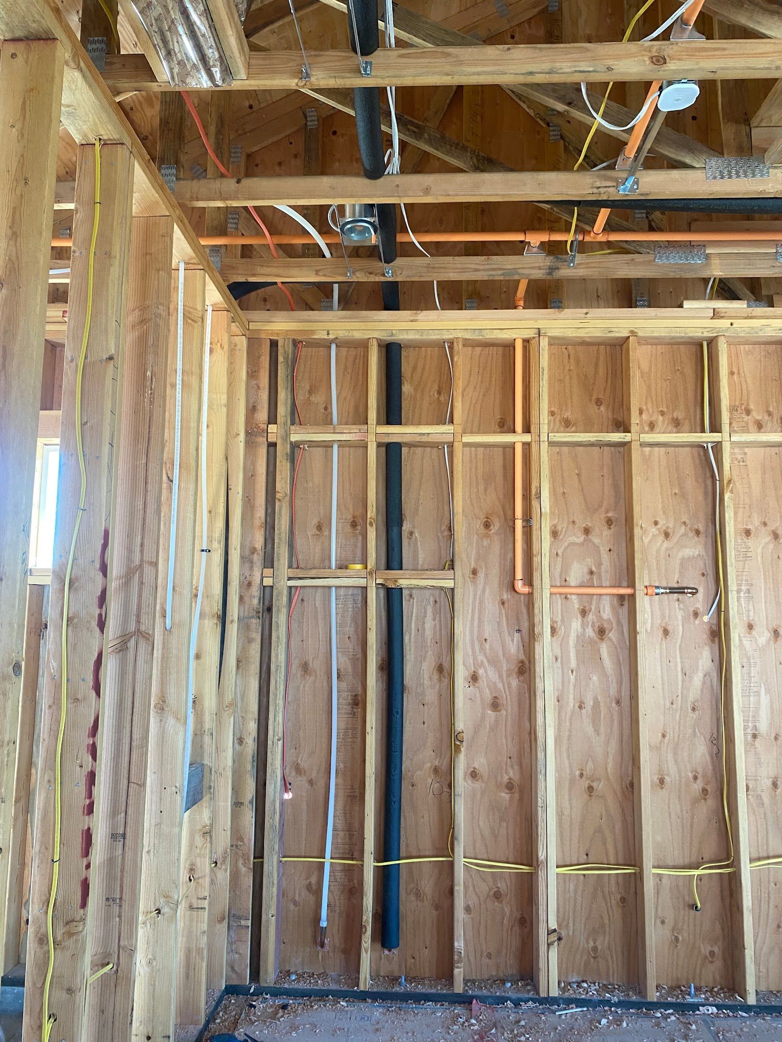 Interior framing with exposed wiring and plumbing in a construction site.