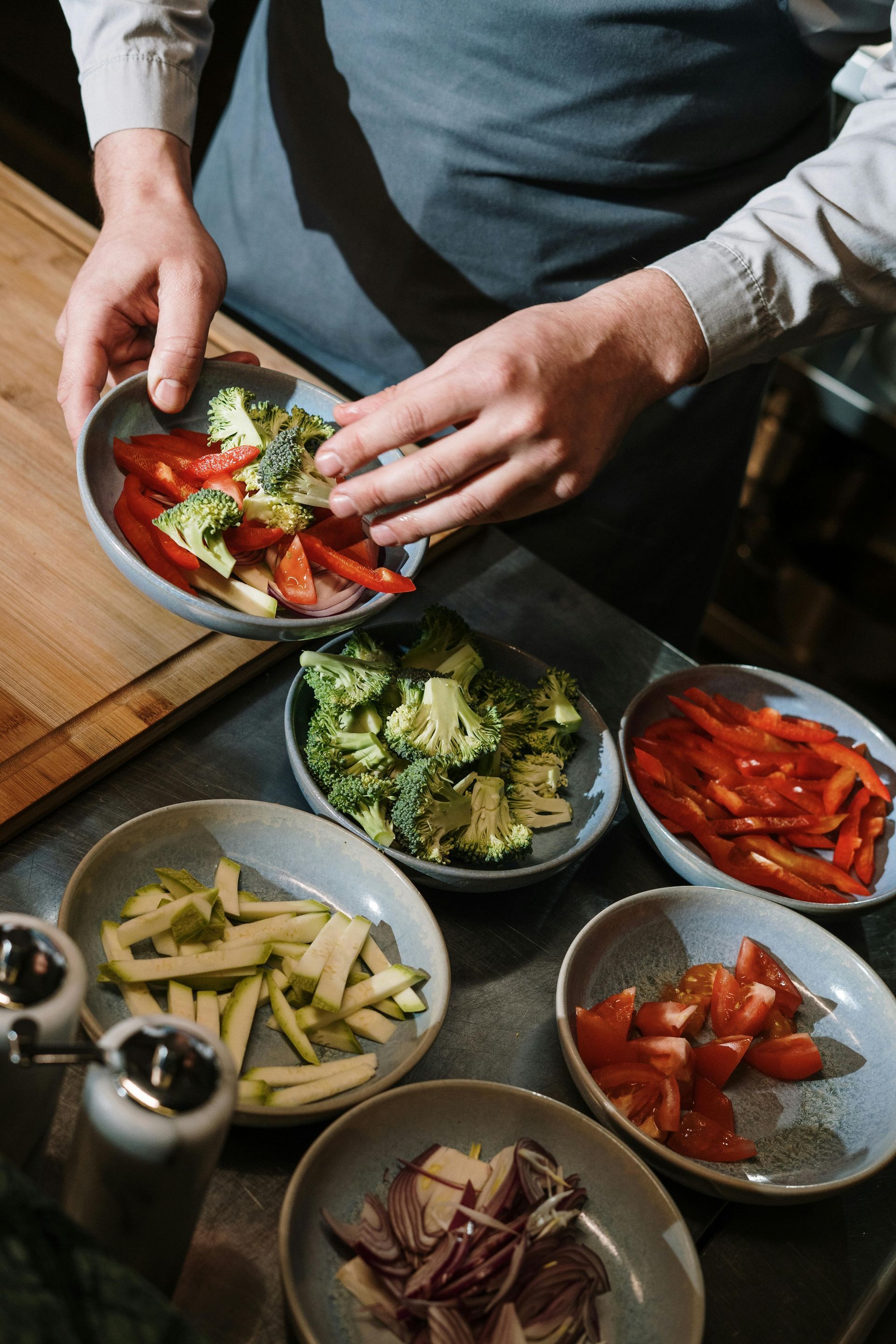 A person is preparing vegetables in bowls on a table.
