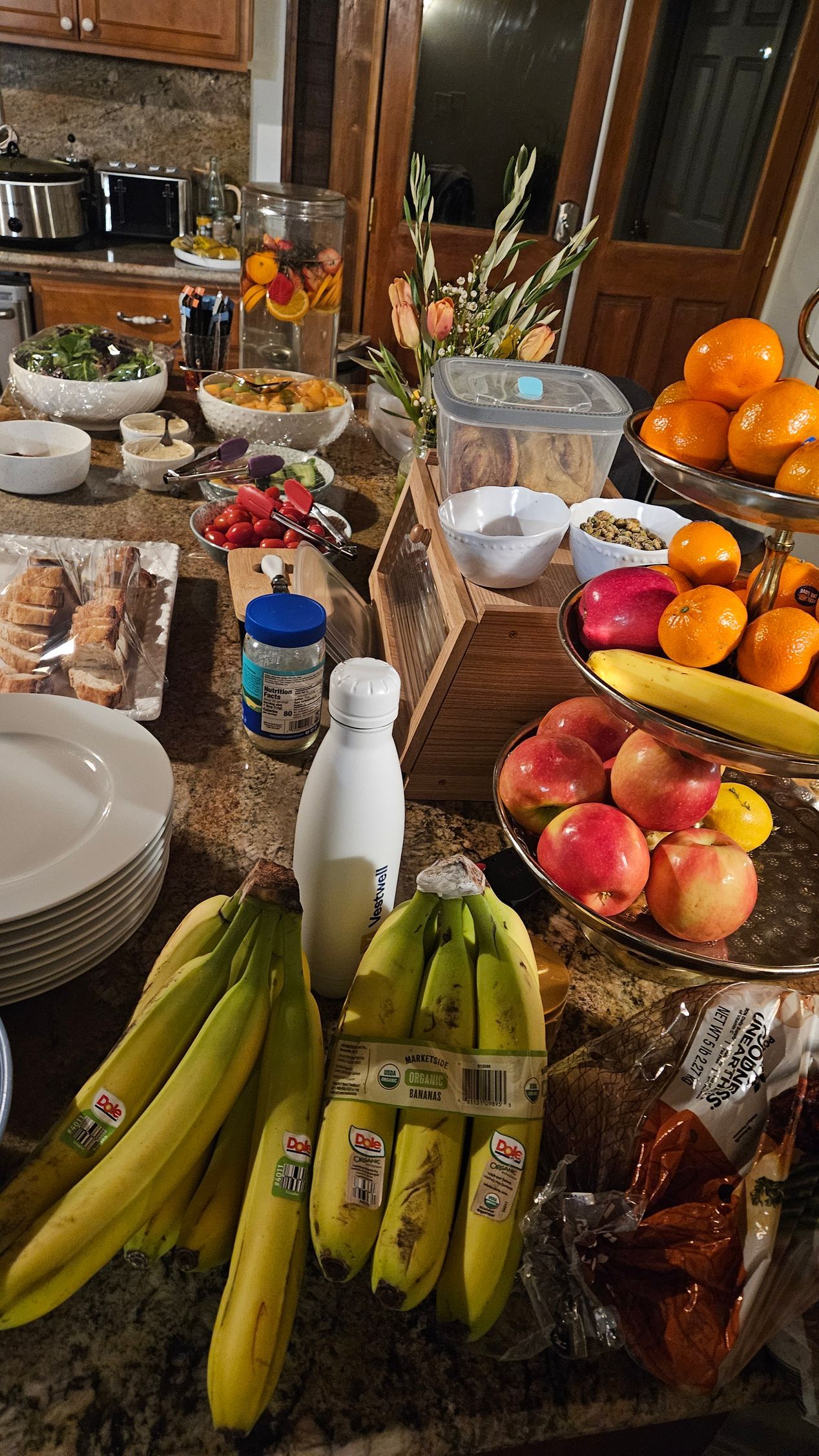A table topped with bananas , apples , oranges and milk.