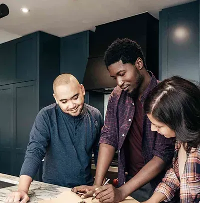 A Group of People Are Standing Around a Counter in A Kitchen — Canberra Kitchen & Bathroom in Fyshwick, ACT
