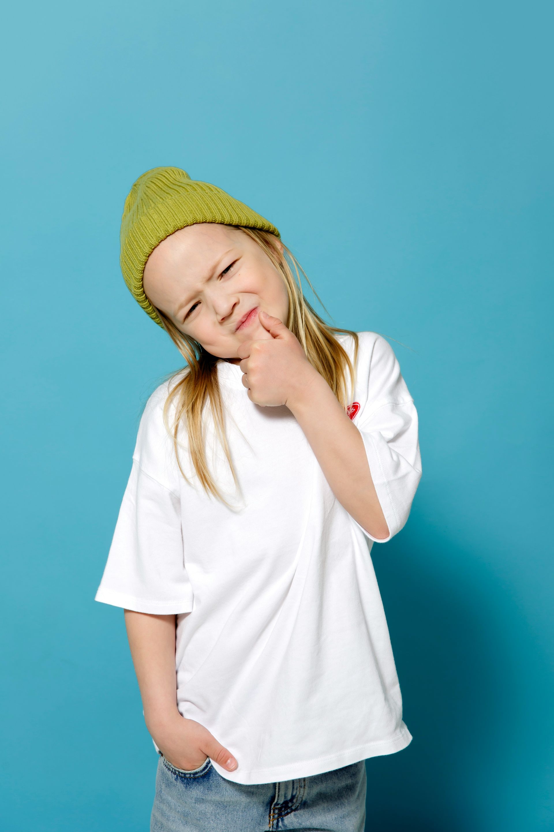Person in a yellow hat and white t-shirt with their hand holding their chin. Their eyebrows are furrowed in concentration.