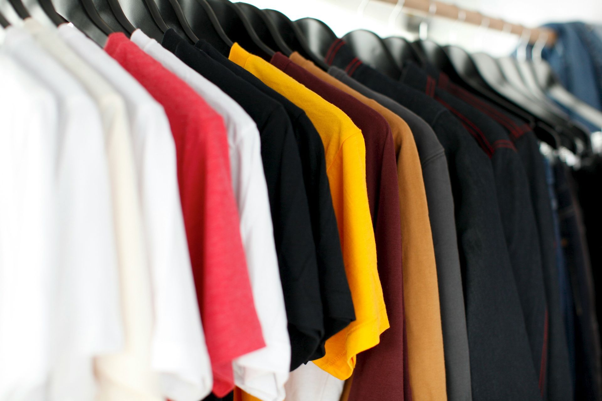 A row of colorful t-shirts are hanging on a rack.