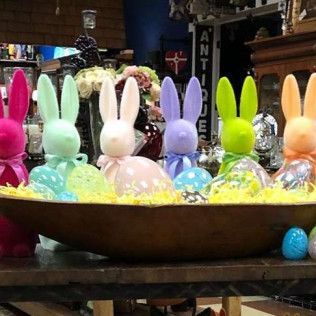 Colorful bunny figurines in a bowl of Easter eggs on a table
