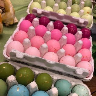 Trays of assorted pastel-colored dyed eggs in cardboard cartons, with greens and pinks visible.
