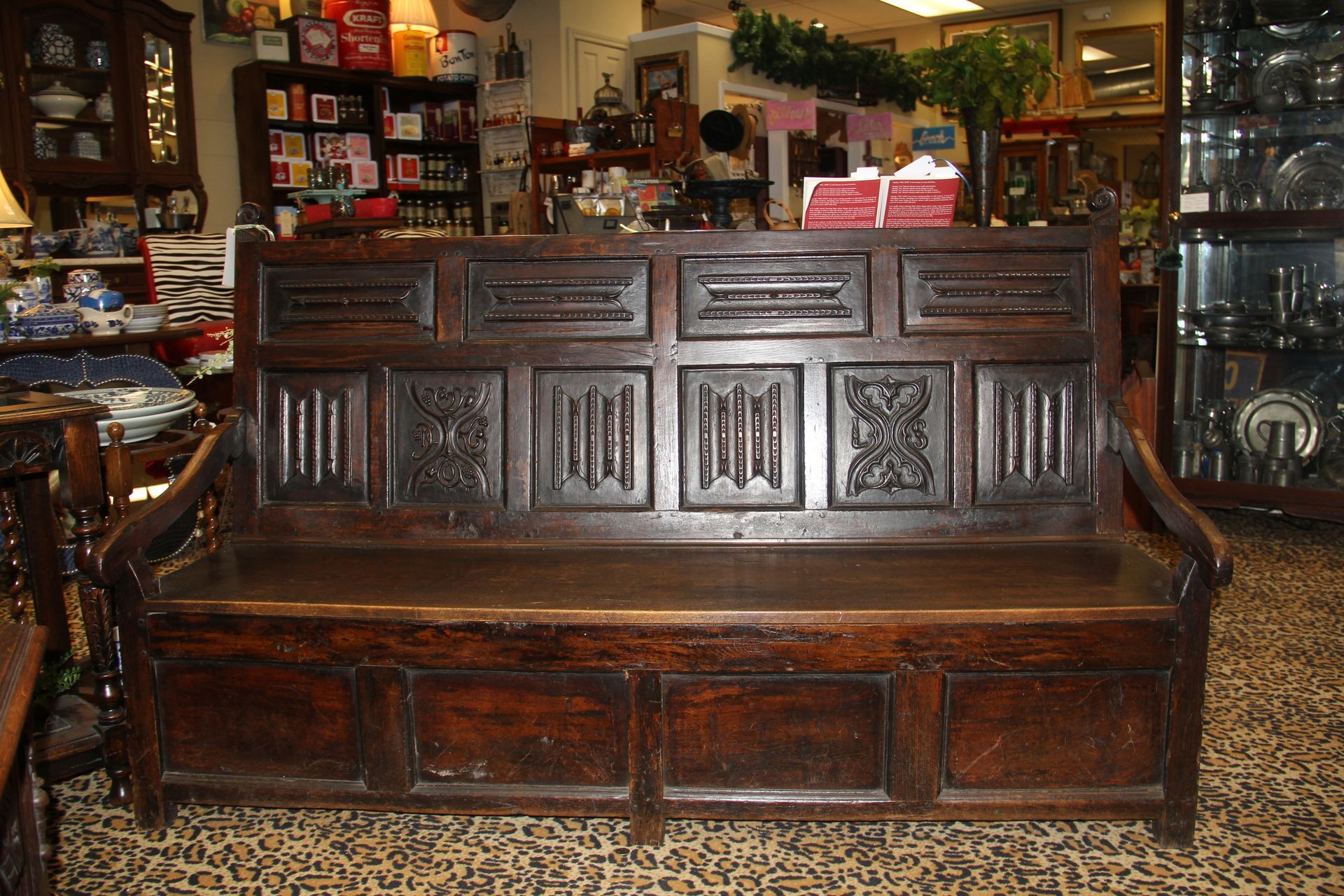Dark wooden bench in a rustic shop interior, with shelves of antiques and decor in the background.