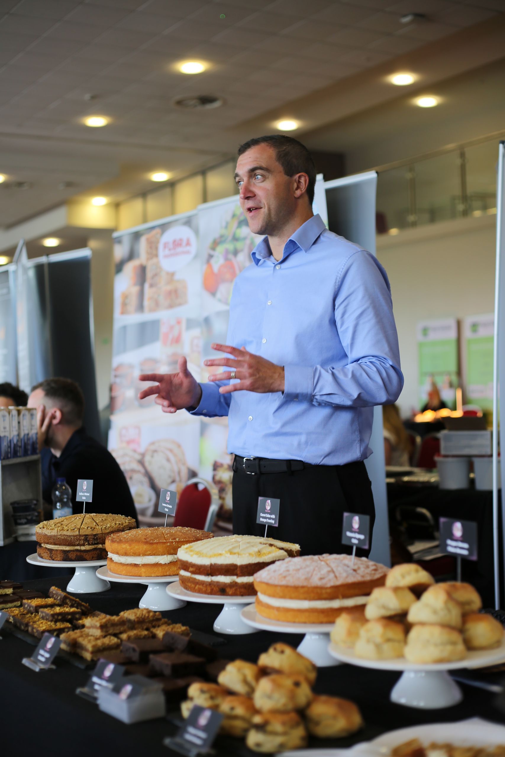 A man in a yellow jacket is talking to another man in a warehouse.