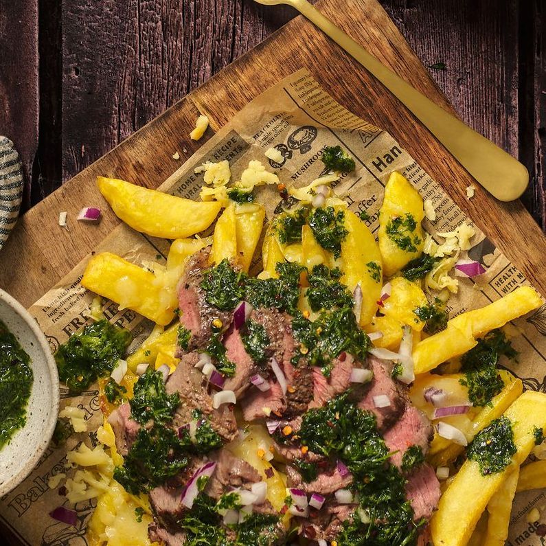 Three plates of food are sitting on a wooden table next to a glass of beer.
