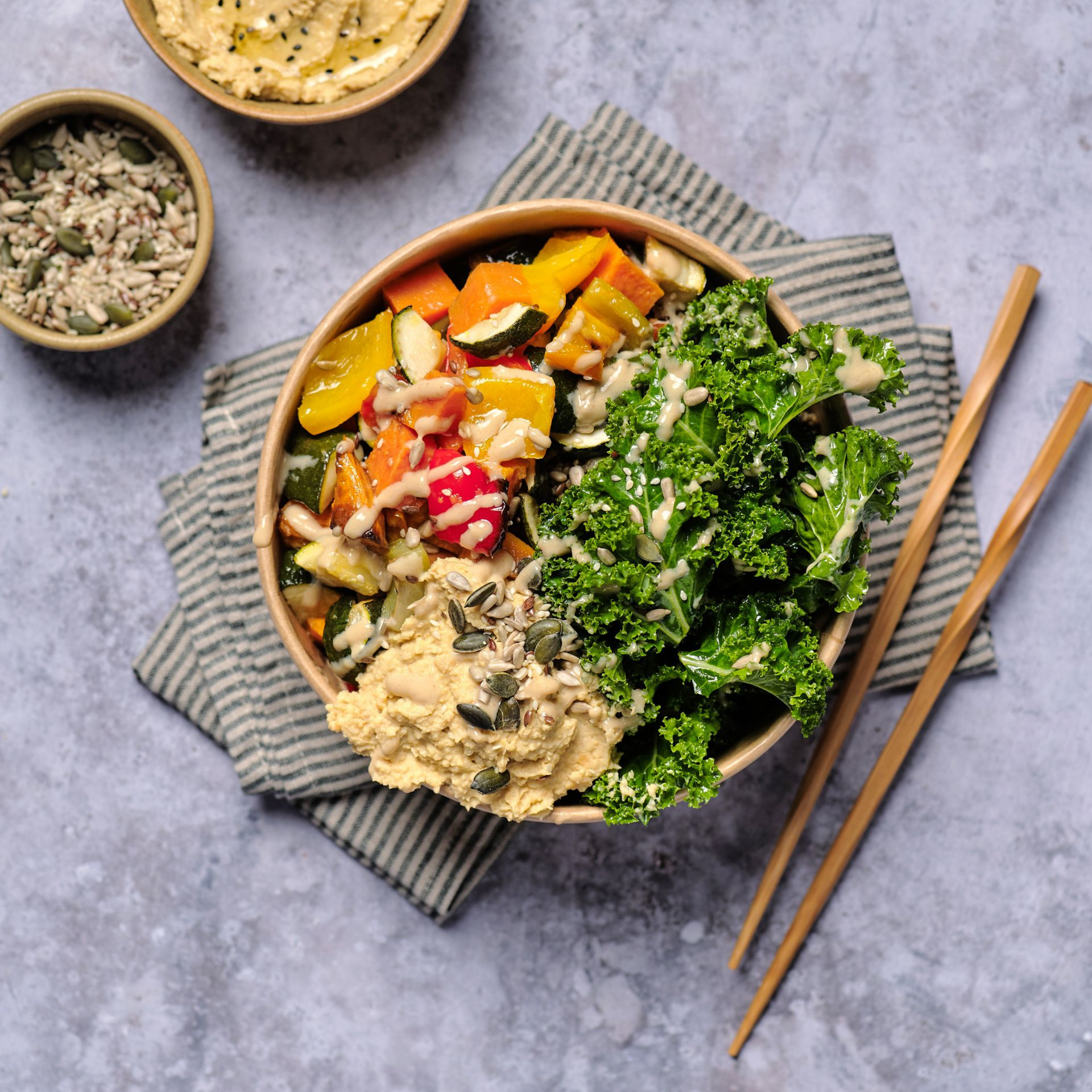 Three plates of food are sitting on a wooden table next to a glass of beer.