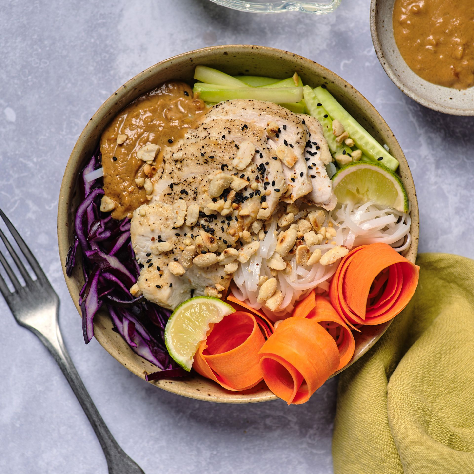 A pan filled with french fries and vegetables next to a bowl of ranch dressing.