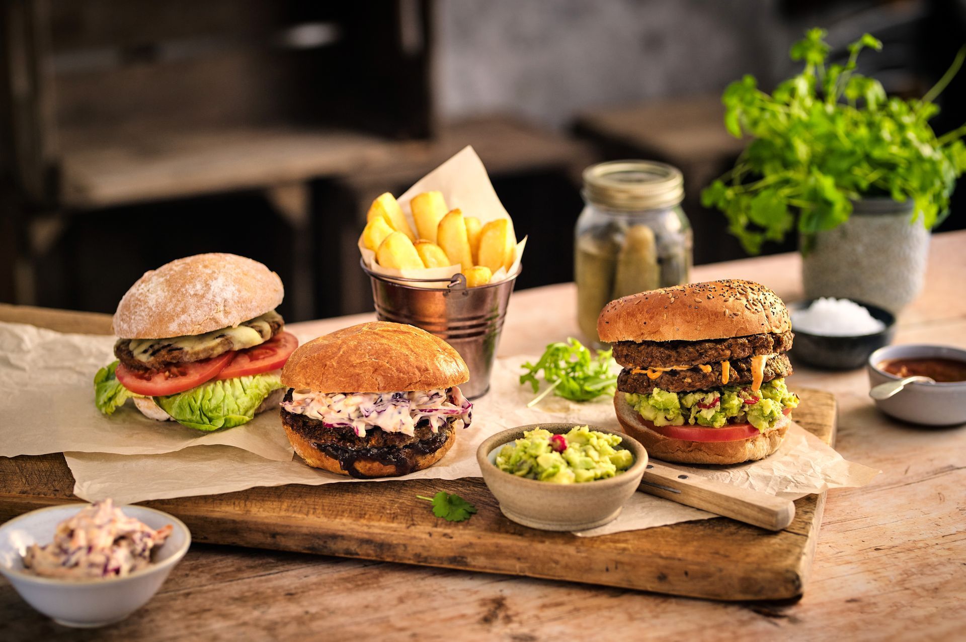 A wooden cutting board topped with three hamburgers and french fries.
