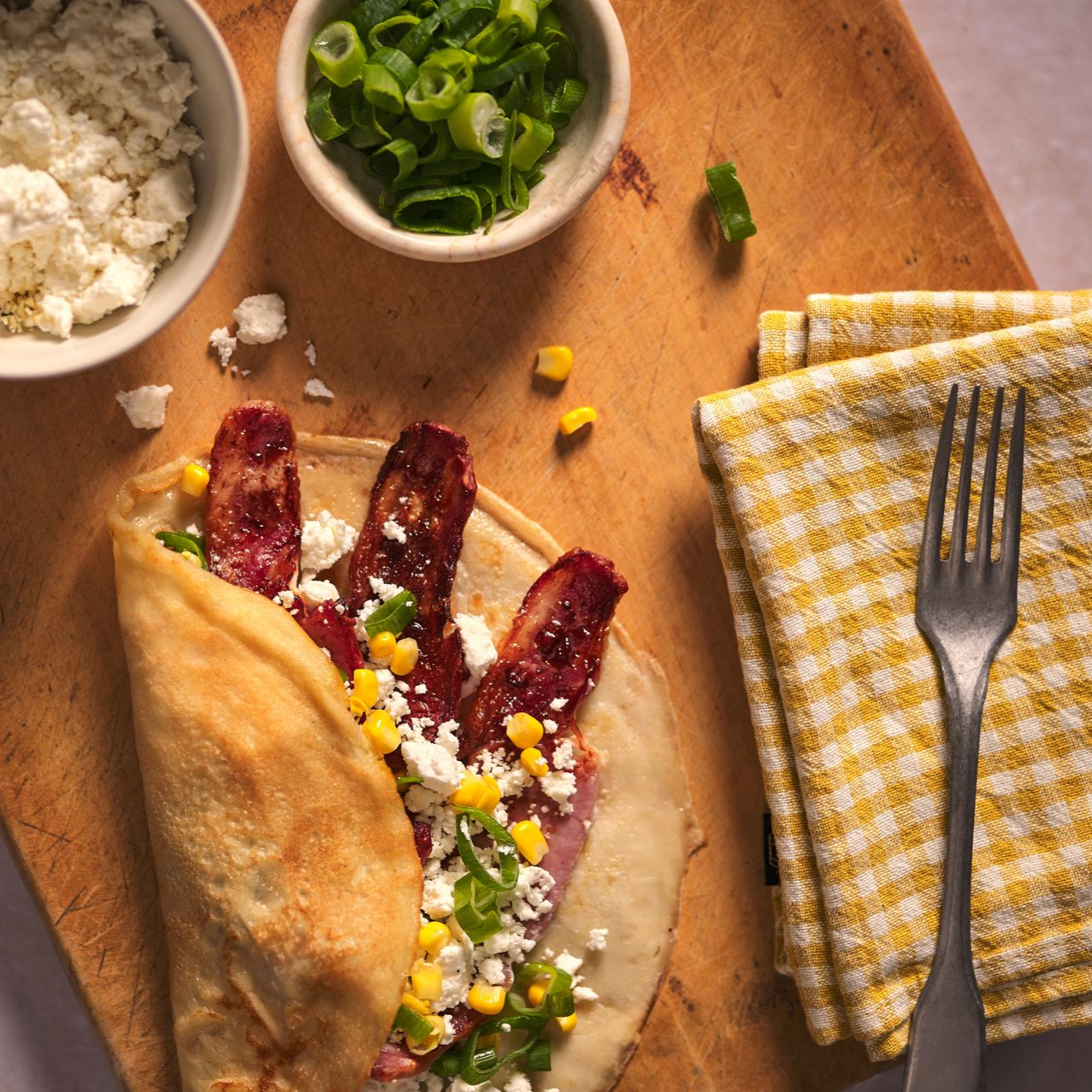 Three plates of food are sitting on a wooden table next to a glass of beer.