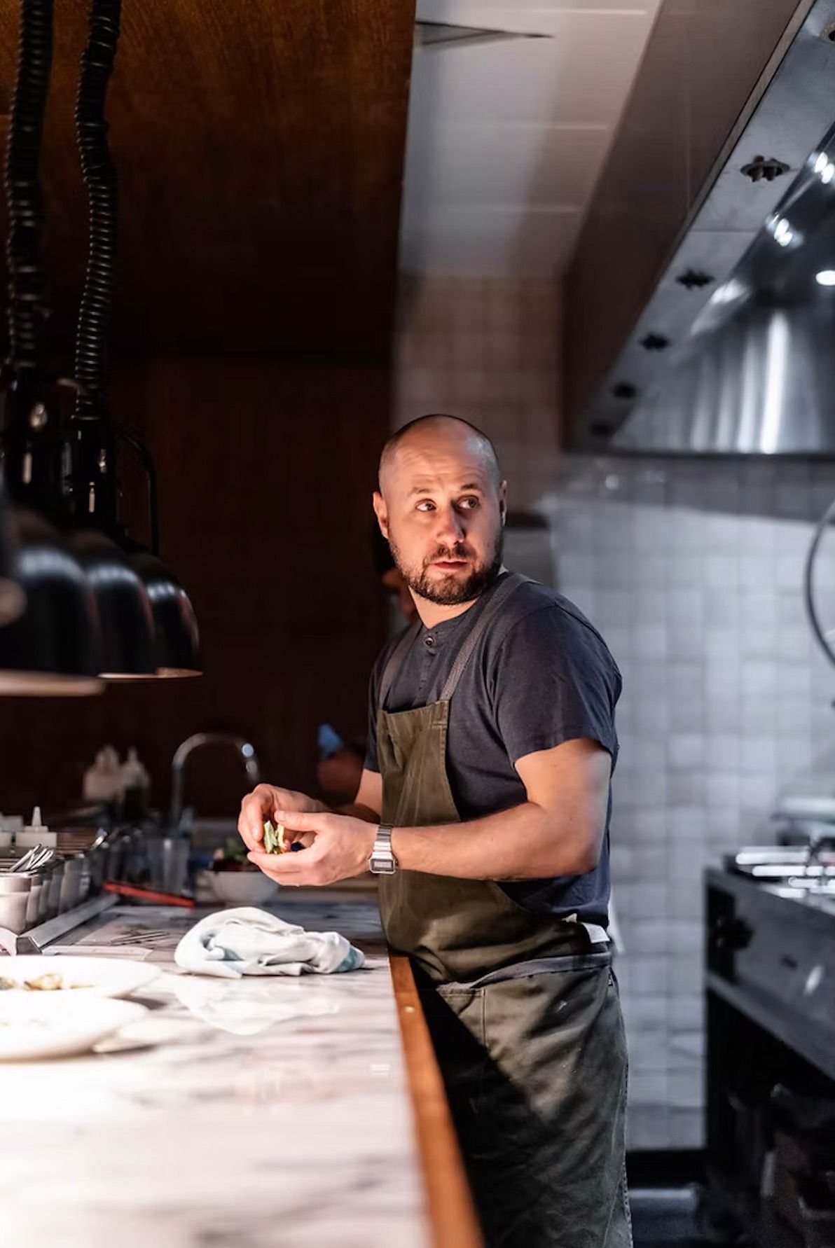 A man with a beard is standing in front of a large house.